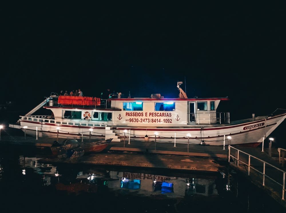 Embarcação Conquista iluminada à noite no píer